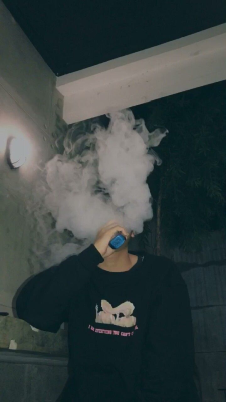 A person using an electronic cigarette, showcasing a Packwoods x Runtz disposable vape in a casual setting.